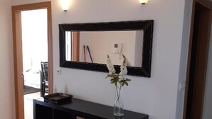 A room with a black console table, a mirror, and a vase with flowers.