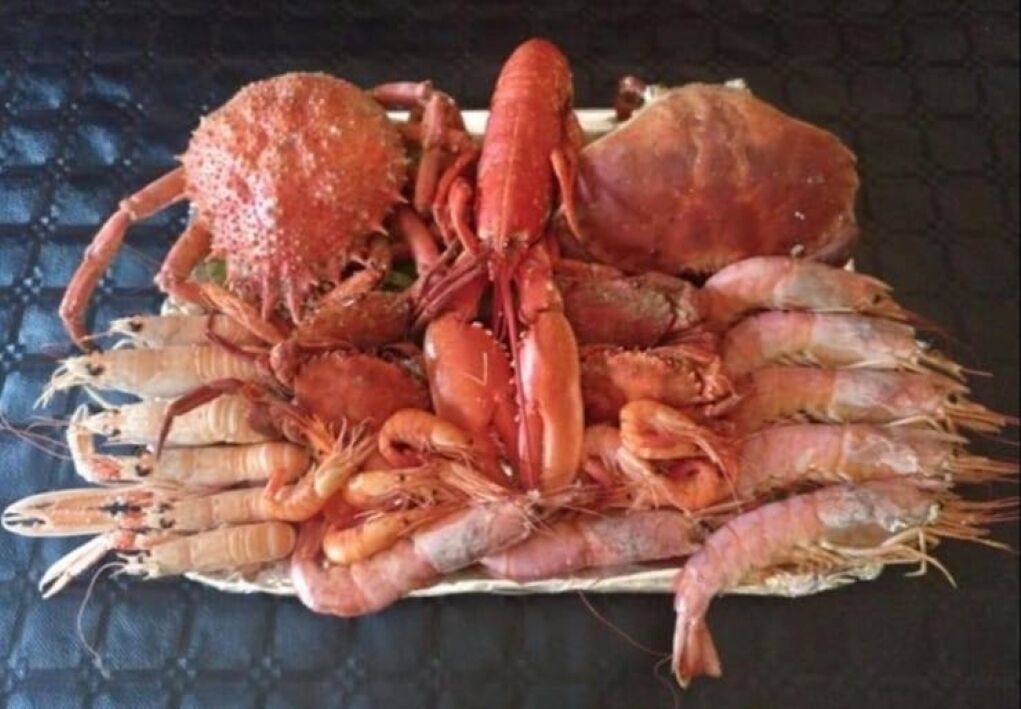 Una cesta con mariscos cocidos, incluyendo langostas y camarones.