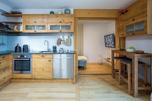 Una cocina compacta con muebles de madera, un lavavajillas Bosch y una cafetera.