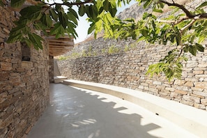 A stone-walled corridor with a concrete floor and a wooden beam structure overhead.