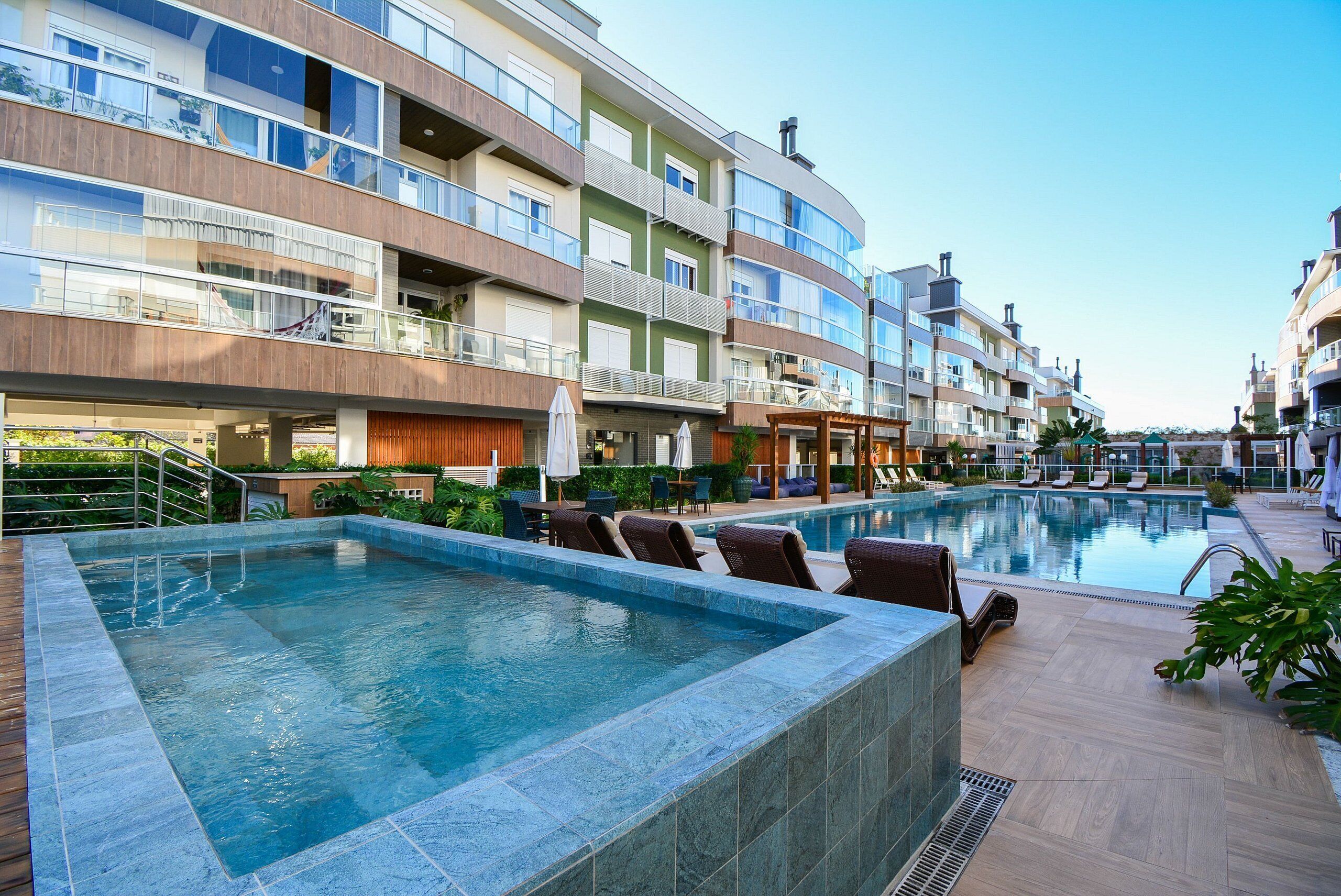 Um hotel moderno com piscina, área de estar ao ar livre e várias varandas.