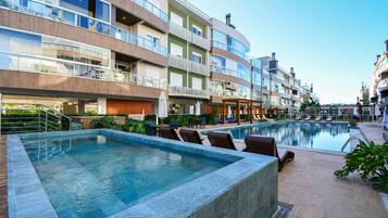 Um hotel moderno com piscina, área de estar ao ar livre e várias varandas.