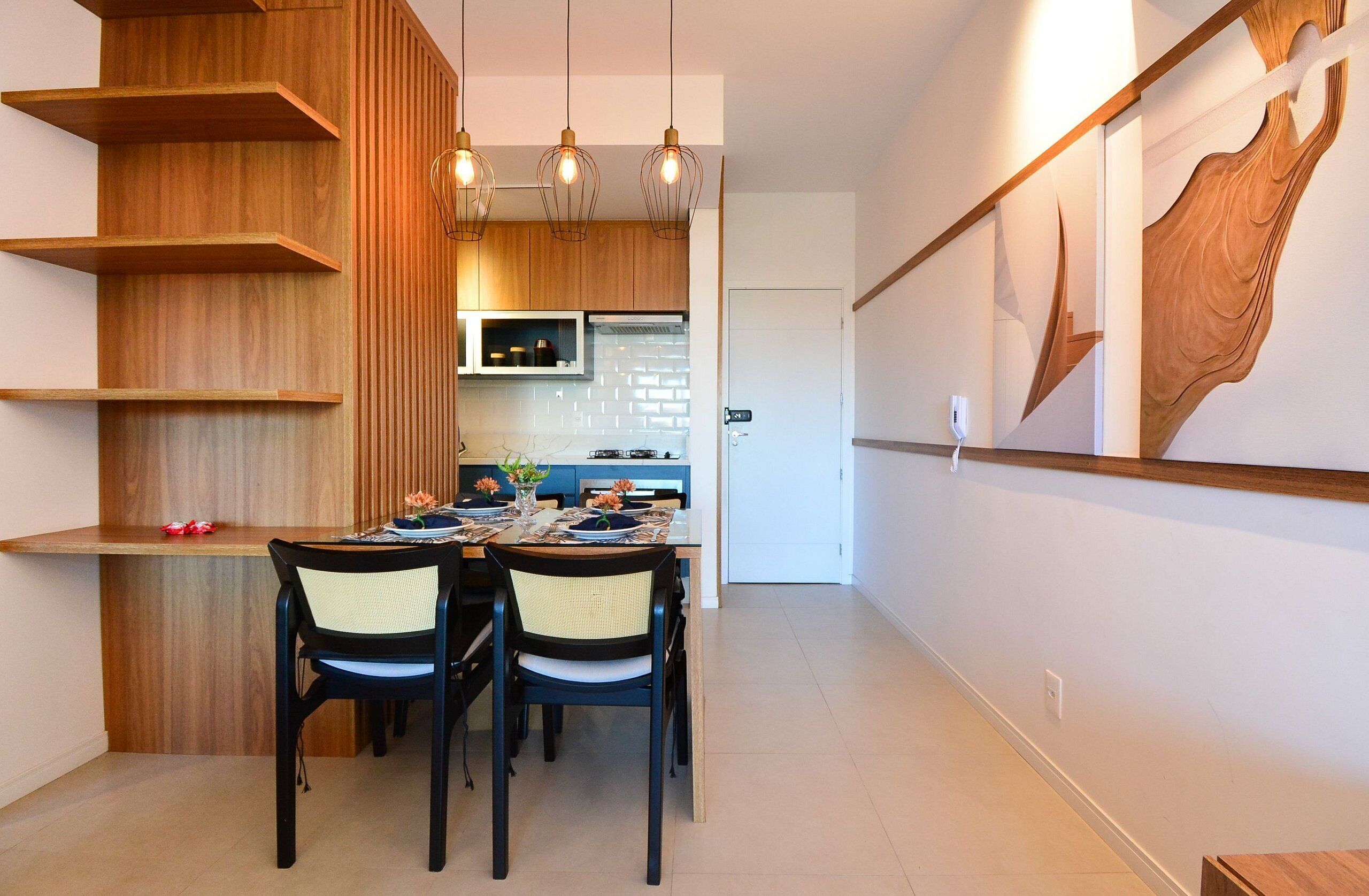 A modern kitchen with wooden cabinetry, a dining table with chairs, and pendant lighting.