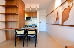 A modern kitchen with wooden cabinetry, a dining table with chairs, and pendant lighting. - SunClub-300 metros da Praia do Campeche (Florianopolis)