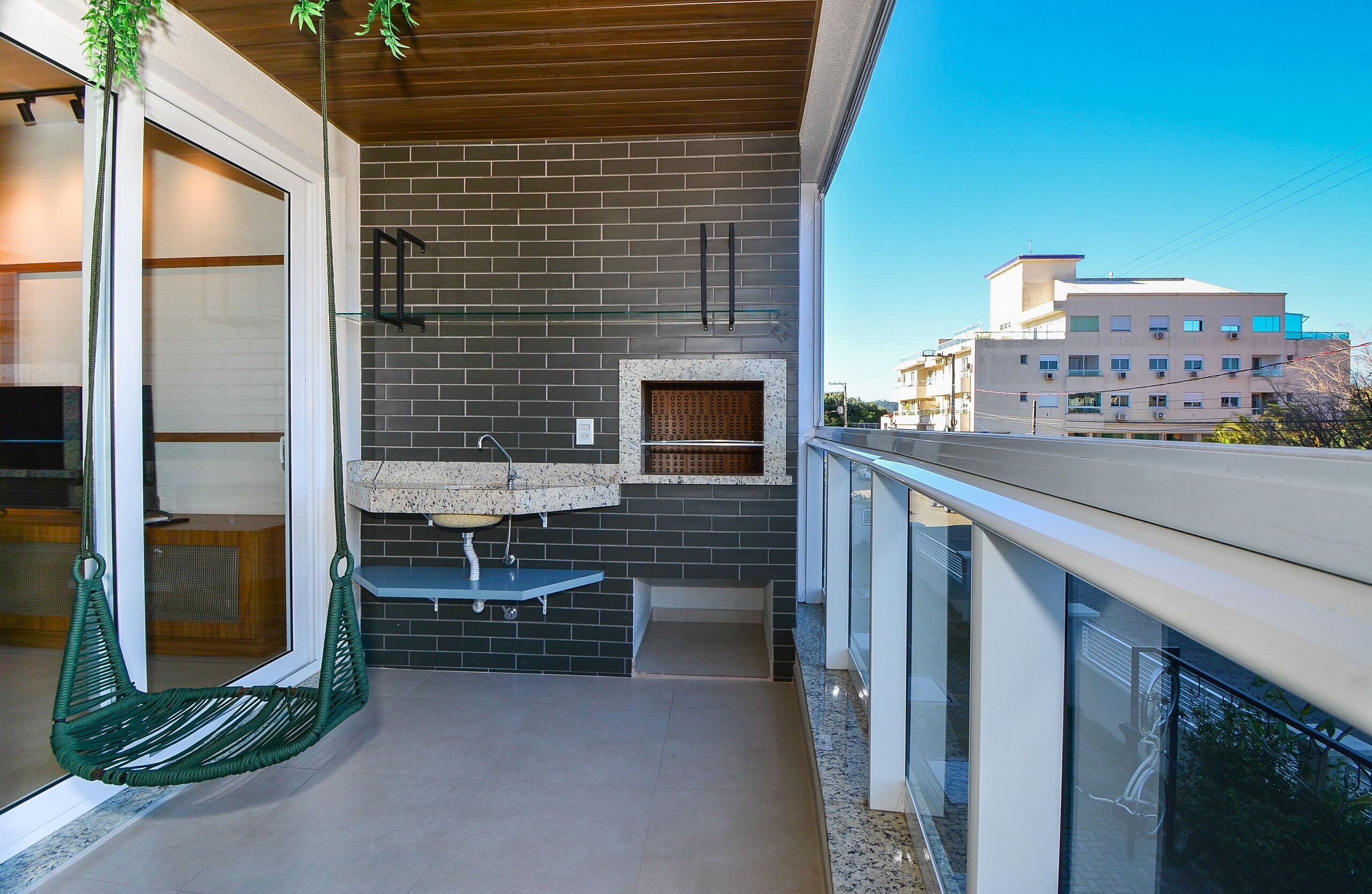 En balkon med hængestol, lille bord og indbygget vask.
