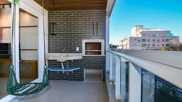 Un balcon avec un fauteuil suspendu, une petite table et un évier encastré.