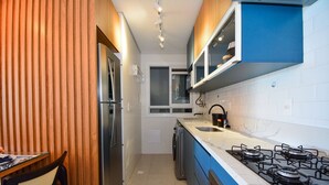 Une cuisine de taille réduite équipée d’une cuisinière à gaz, d’un réfrigérateur et d’un évier.