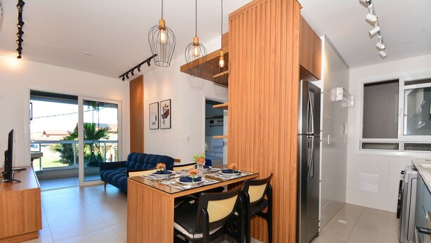 Une cuisine moderne dotée d’un îlot central, d’un coin repas avec des chaises et d’un réfrigérateur.