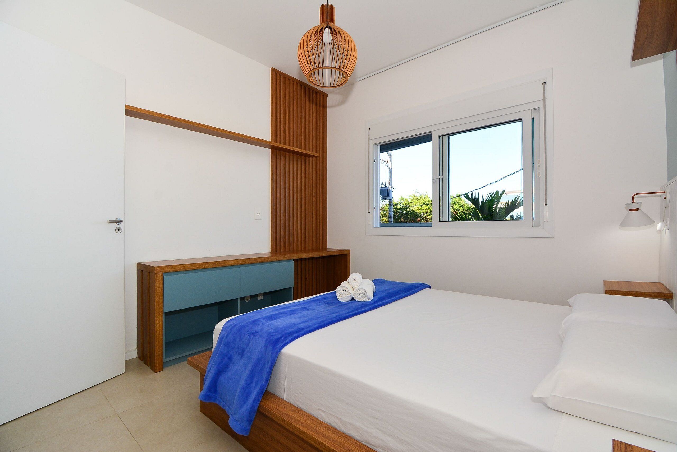 A bedroom with a bed, a window, a wardrobe, and a bedside table.