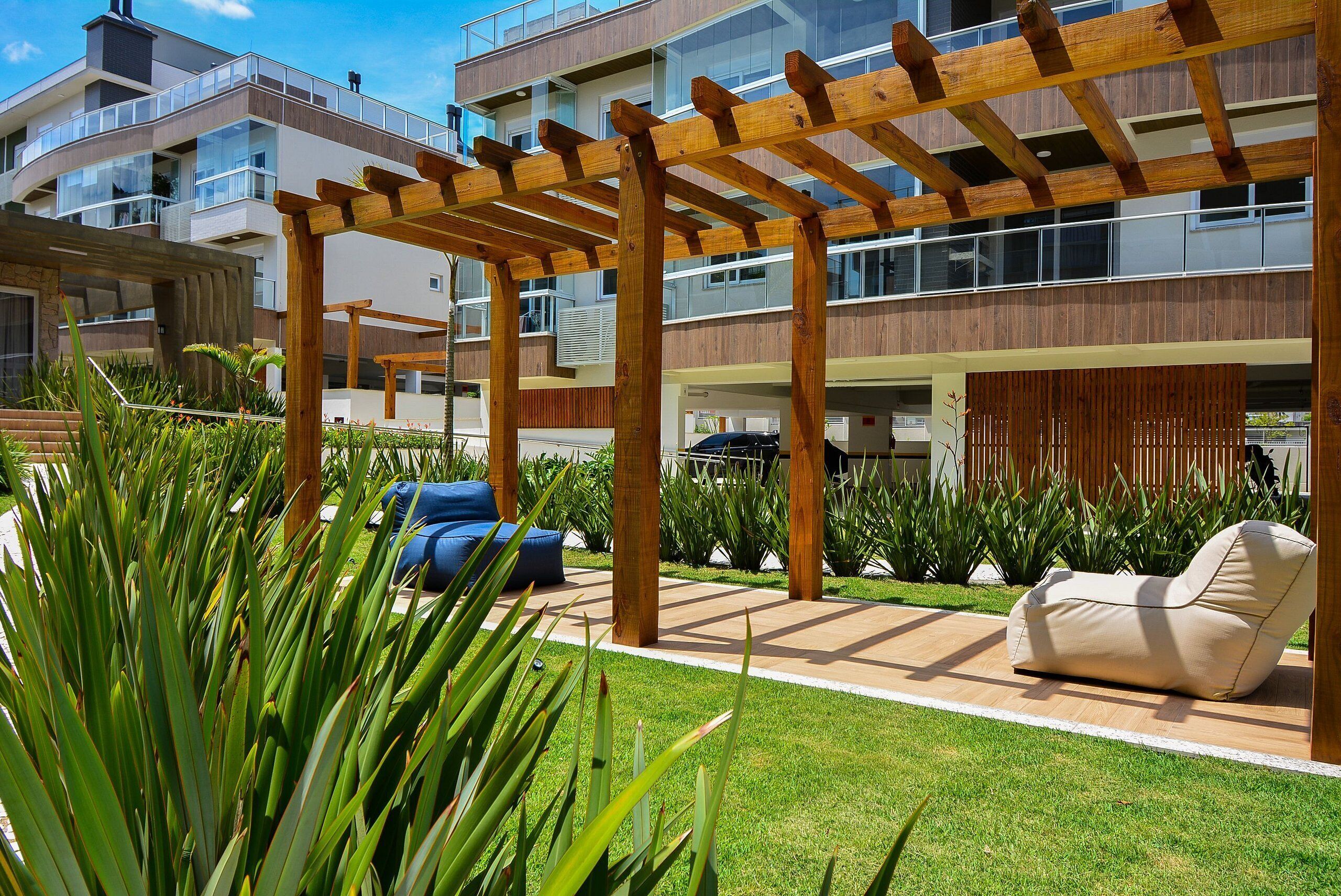 A modern outdoor area with a wooden pergola, a beige lounge chair, and a blue sofa.