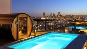 A rooftop infinity pool with a city skyline view, a sauna, and a glass-enclosed area. - Luxury penthouse in enchanting Denver with bar, gym, pool, sauna & more (Denver)