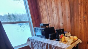 A wooden cabin interior with a table set for coffee, a coffee maker, and mugs. - Cabin Style Private Studio  (Giroux)