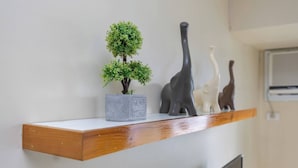 Een plank met een bonsaitje, een dinosaurusbeeldje en een klein beeldje.