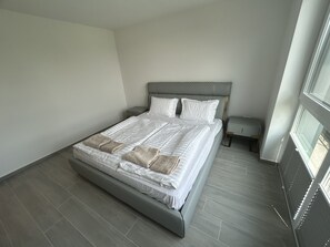 Ein modernes Schlafzimmer mit einem großen Bett, einem Nachttisch und einem Fenster.