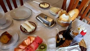A breakfast setting with a variety of food items including fruits, bread, and beverages on a table. - Pousada Cabocla (Santarém)