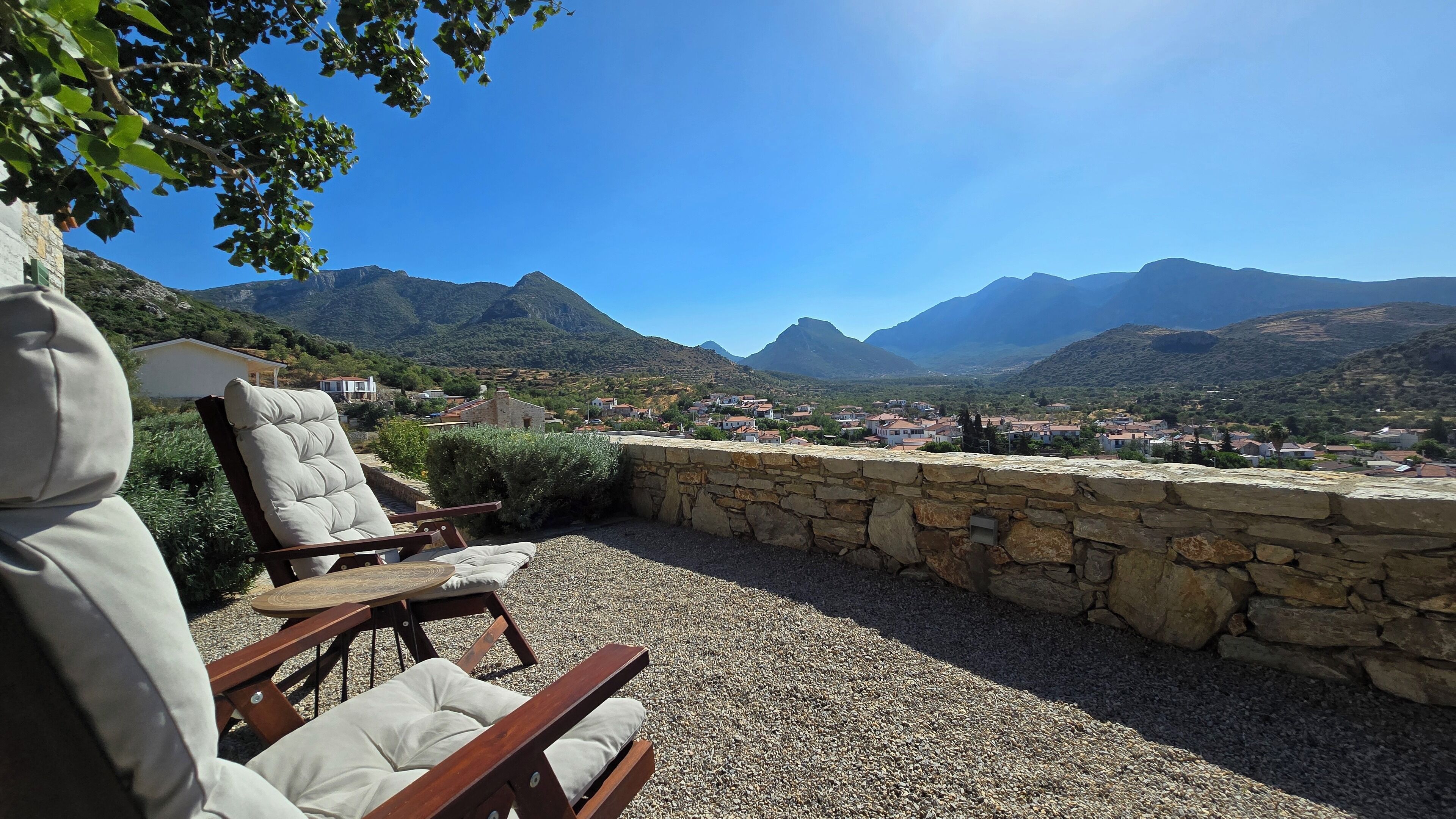 A stone wall with a view of a village and mountains.