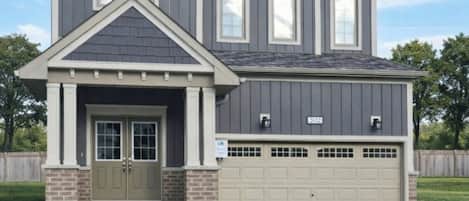A two-story house with a garage, a front porch, and a well-maintained lawn.