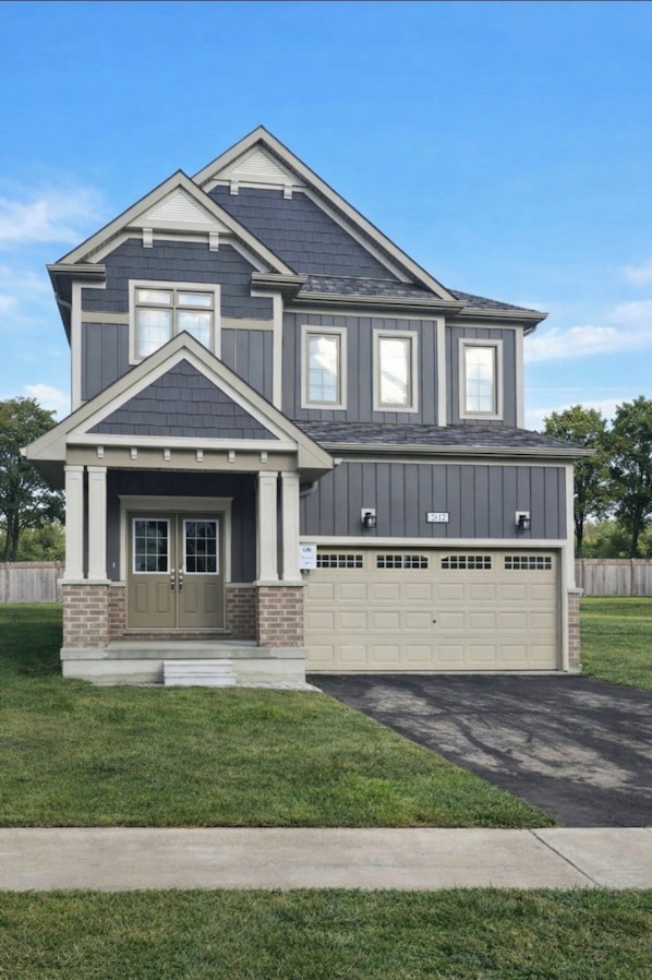 A two-story house with a garage, a front porch, and a well-maintained lawn.