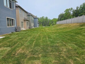 A residential area with houses, a well-maintained lawn, and a wooden fence.