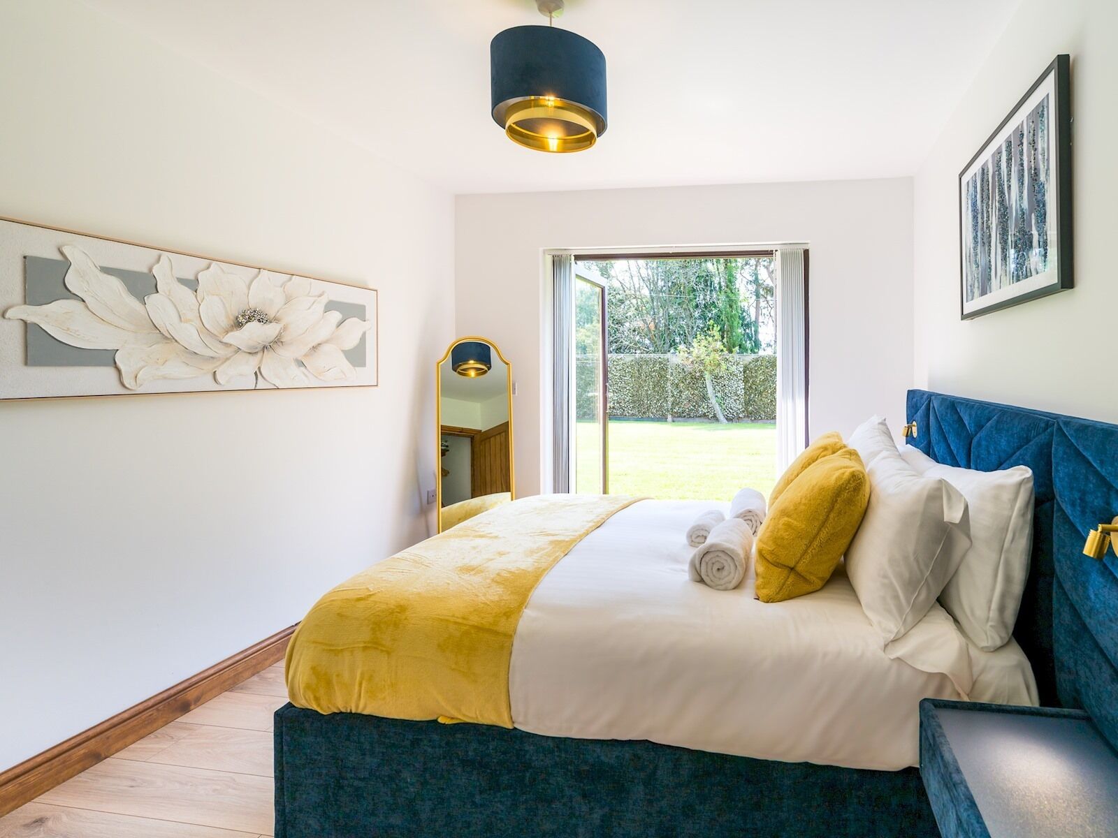 Ein Schlafzimmer mit einem Bett, einem großen Fenster und einem Spiegel.