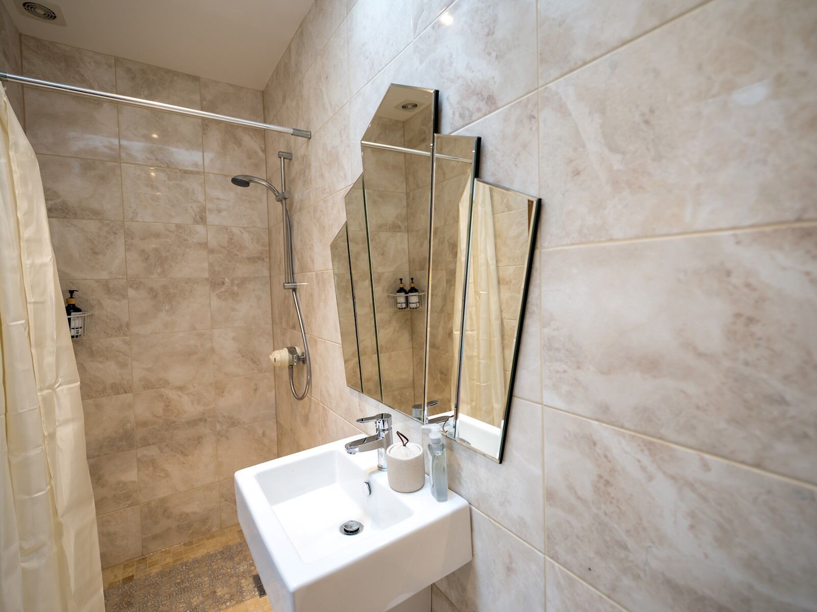A modern bathroom with a shower, a sink, and a large mirror.