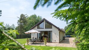 Une maison moderne à deux étages, dotée d’un patio, d’une voiture garée dans l’allée et d’une pelouse bien entretenue.
