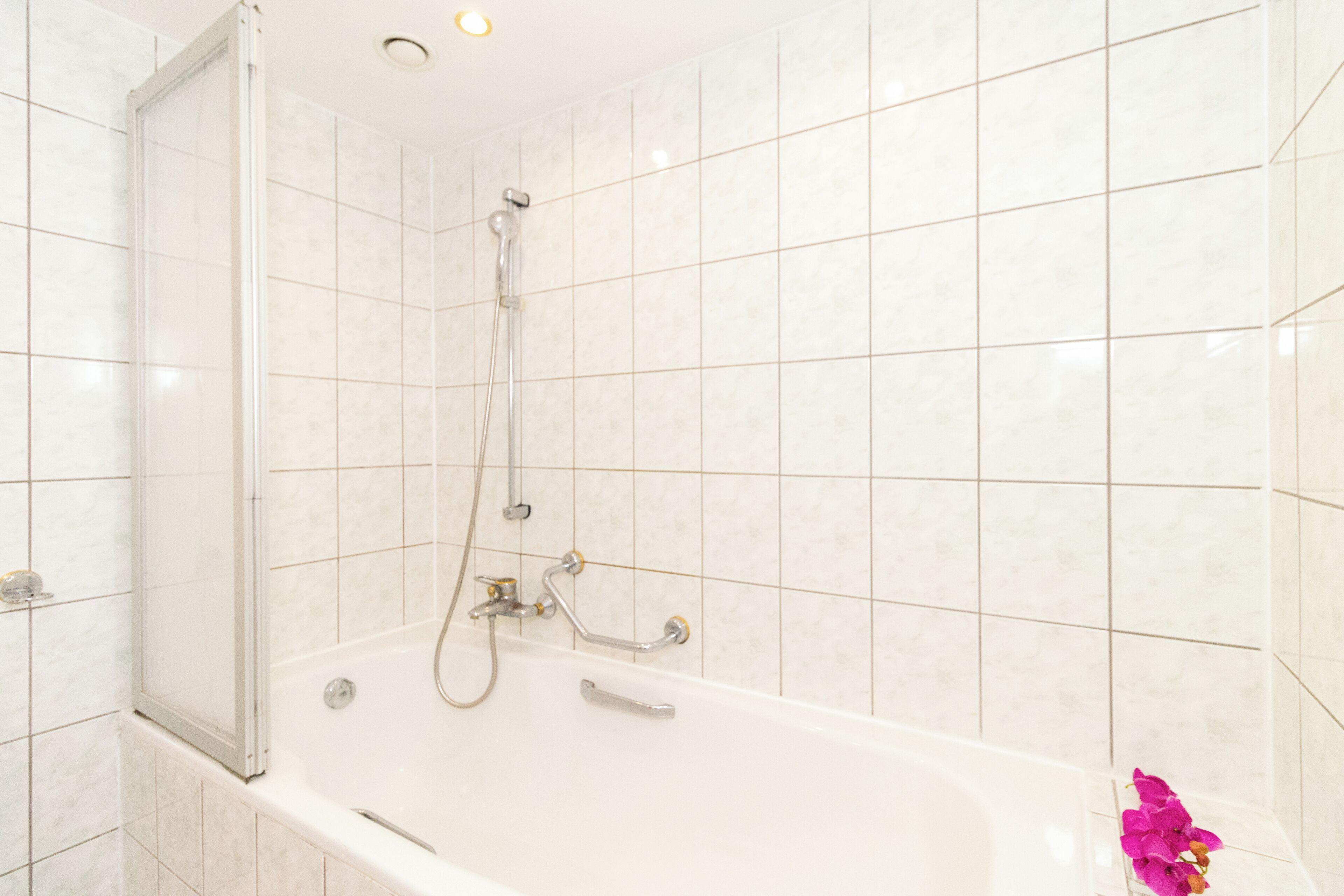A bathroom with a white bathtub, a shower, and a glass-enclosed shower area.