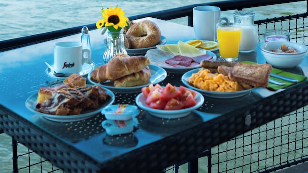 A breakfast table with various foods and a view of a river and hills. - Aquamarina Hotel Visegrád (Visegrád)