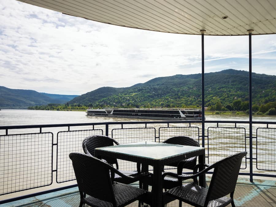 Une table et des chaises sur une terrasse offrant une vue sur une rivière et des montagnes.