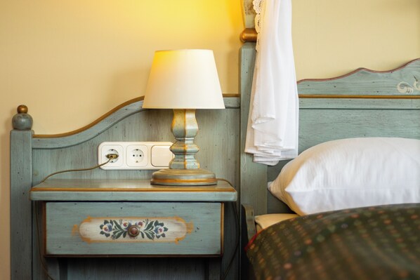 A wooden nightstand with a lamp, a power outlet, and a decorative drawer. - Aquamarina Hotel Visegrád (Visegrád)