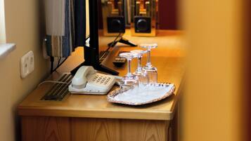 A wooden desk with a telephone, a lamp, and a tray with wine glasses.