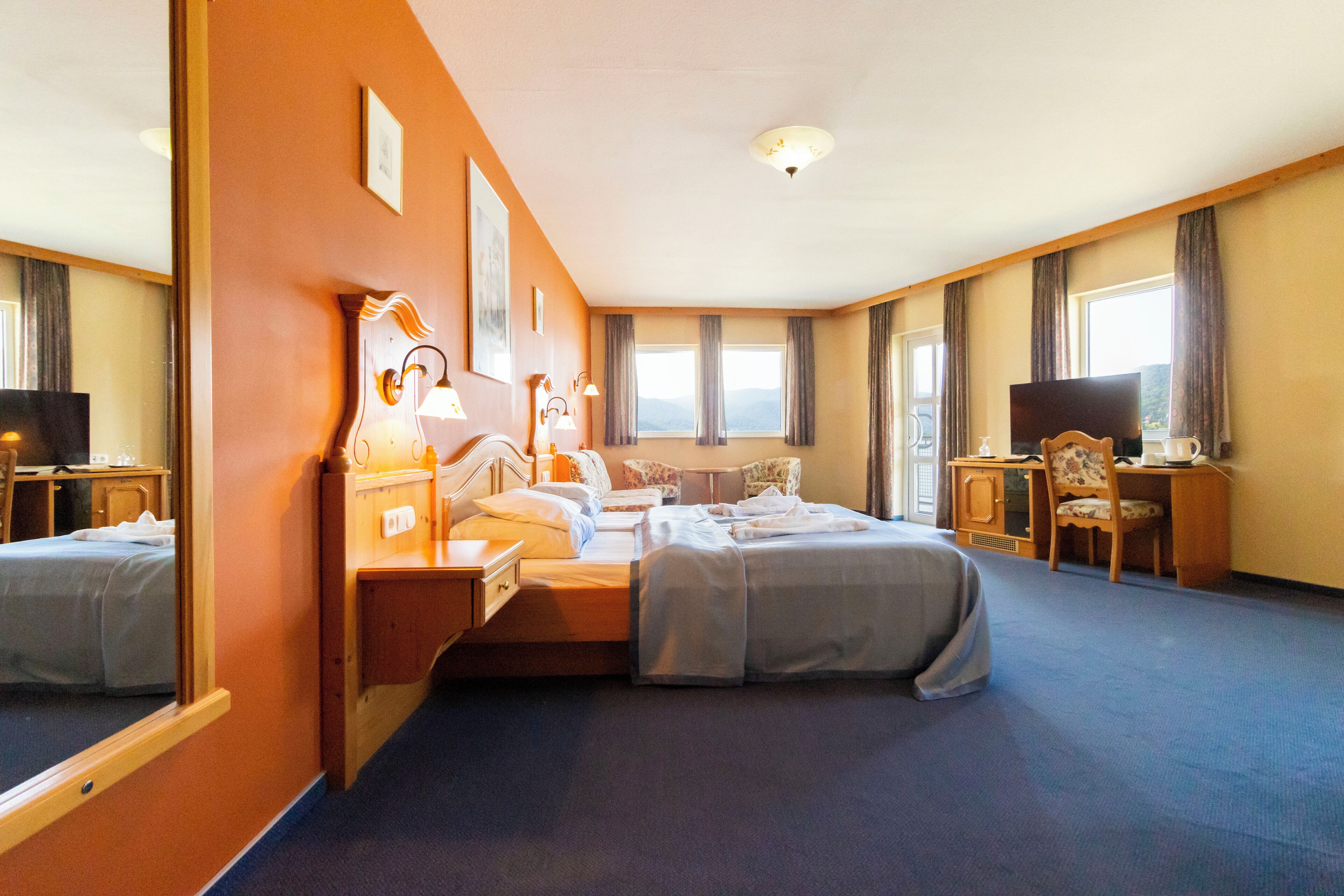 Een hotelkamer met twee bedden, een bureau, een stoel, een televisie en een raam met gordijnen.