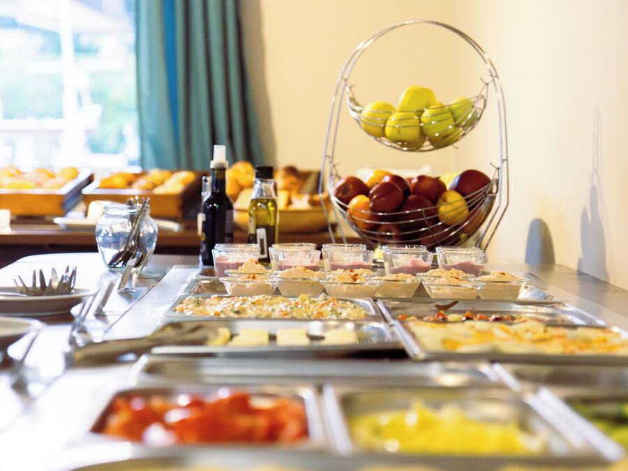 A buffet table with various food items and a fruit basket.