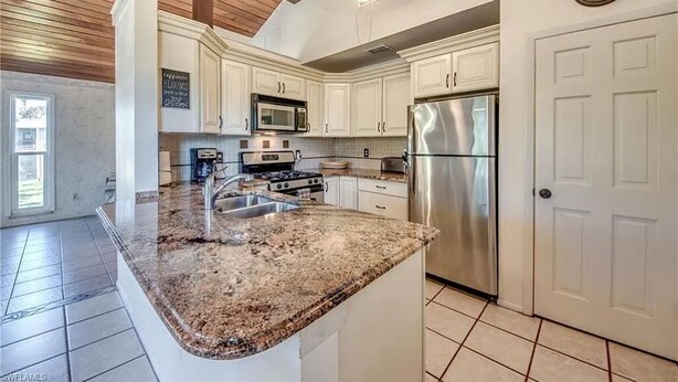 A kitchen with white cabinets, stainless steel appliances, and a granite countertop.