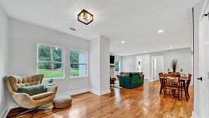 A spacious living area with hardwood flooring, a tufted armchair, a green sofa, and a dining table with chairs. - Modern Farmhouse in the City -  4-bedroom house in charming Atlanta (Atlanta)