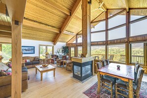 Amplia sala de estar con chimenea, muebles de madera, ventanas grandes y vistas al exterior.