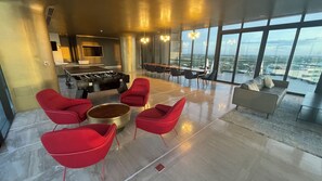 A spacious room with a foosball table, red chairs, a sofa, and a large window offering a city view. - Hermoso estudio en Merida Cabo Norte Torre Adamant junto a Plaza La Isla (Mérida)