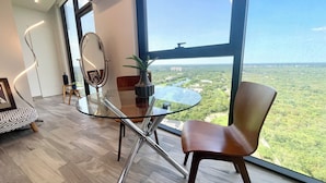A modern room with a glass table, a round mirror, and a view of a green landscape through large windows. - Acogedor estudio en Adamant Cabo Norte en Merida, perfecto parejas o home office (Mérida)