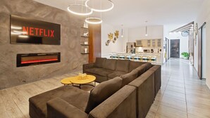 A modern living room with a sectional sofa, a fireplace, and a Netflix sign.