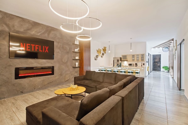 Una sala de estar moderna con un sofá modular, una chimenea y el logotipo de Netflix.