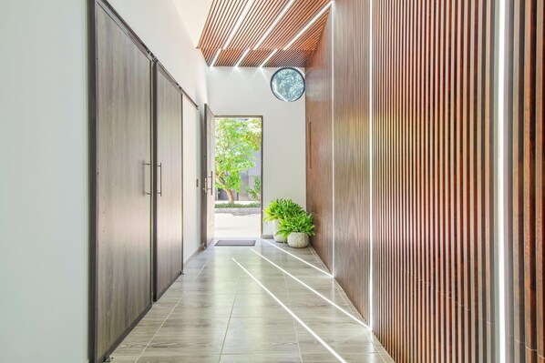A hallway with a modern design, featuring a wooden slatted wall, a potted plant, and a view of the outdoors. - 12-bed with AC , All inclusive tourist accommodation and Experiences (Unknown)