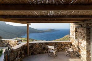 A stone-walled outdoor seating area with a view of the sea and hills. - Koukios Cells Traditional Cycladic Farmhouse (Serifos Island)