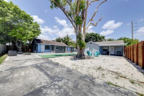 Un immobile residenziale con vialetto, un albero e due case.