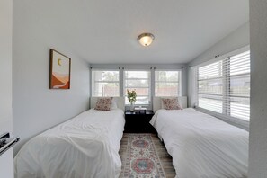 Una camera da letto con due letti, una finestra con persiane, una plafoniera e un quadro appeso al muro.