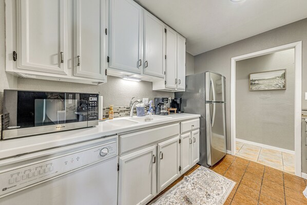 A modern kitchen with white cabinets, stainless steel appliances, and a tiled backsplash.
