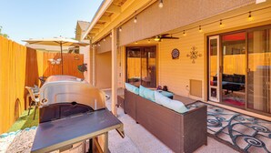 Une terrasse avec un barbecue, des sièges d’extérieur et un espace abrité doté d’une porte coulissante.