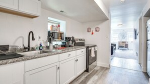 Eine moderne Küche mit weißen Schränken, Edelstahlgeräten und einer Arbeitsplatte aus Granit.