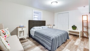 Ein Schlafzimmer mit Bett, Nachttischen, einer Bank und einer Lampe.