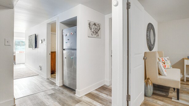 Eine moderne Küche mit einem Edelstahl-Kühlschrank, Holzboden und einem beigen Stuhl mit Sitzkissen.