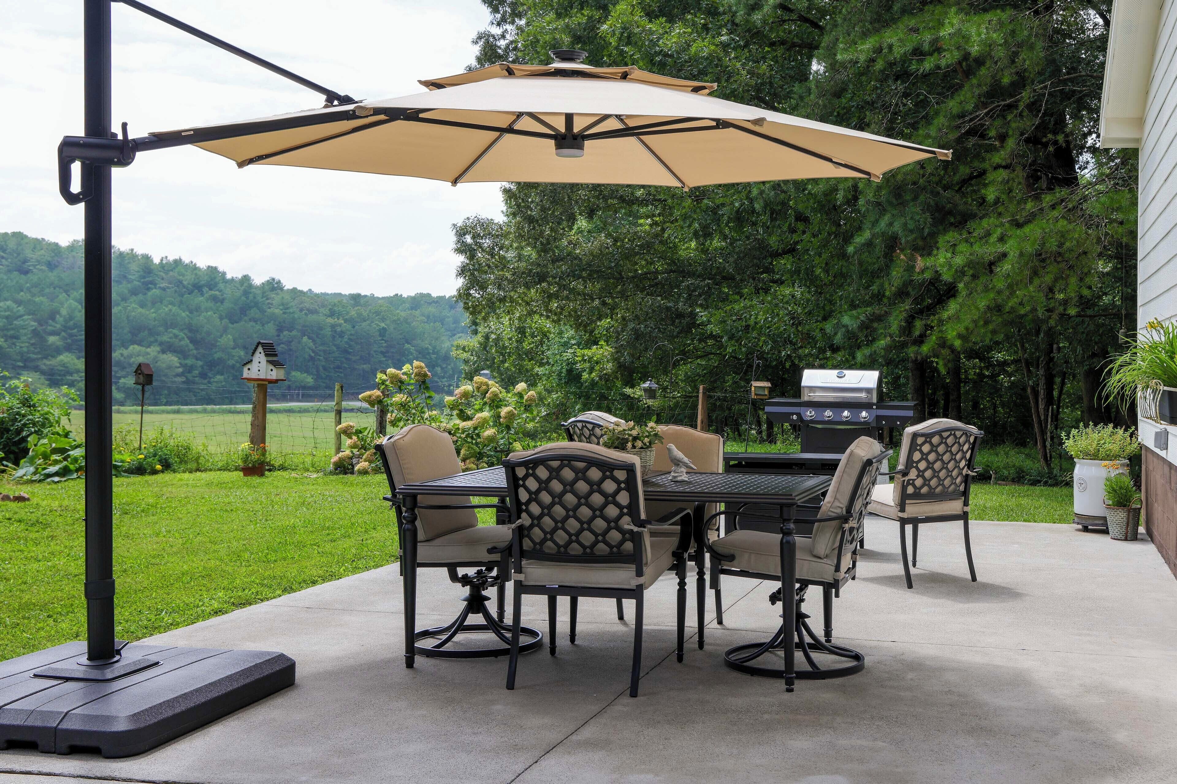Une terrasse extérieure avec une table et des chaises, un barbecue et un grand parasol.